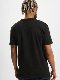 Sort bomulds T-shirt med løstsiddende pasform, korte ærmer og rund hals. Enkel design uden synlige mønstre eller accenter.