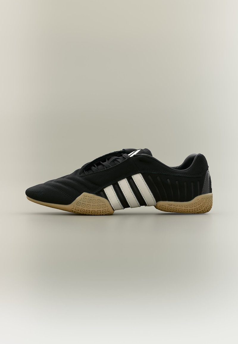 Μαύρο αθλητικό παπούτσι με λευκές ρίγες και μπεζ υφασμένο πάτο σε ουδέτερο φόντο, εμφανίζεται σε πλαϊνή όψη.