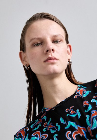 Black top featuring a colorful abstract pattern in red, teal, and blue. Round neckline with a smooth texture and short sleeves.