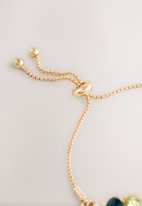 Gold-toned bracelet with a textured chain design, featuring a smooth circular bead and two round accents at the ends.