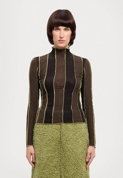 Haut à manches longues avec col montant, en tissu noir transparent avec des rayures verticales vertes ; associé à une jupe verte texturée.