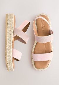 Sandales espadrilles roses avec deux larges brides, une semelle intérieure rembourrée et une semelle en jute tressé. Texture lisse et design à bout rond fermé.