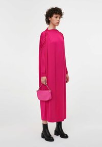 Fuksiaroosa maxi-kleit drapeeritud varrukatega, täiendatud väikese roosa käekotiga. Modell kannab musti kontsaga pahkluukomme. Sile tekstuur.