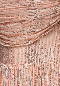 Roségoldfarbenes Paillettenstoff mit drapiertem Textur, versehen mit vertikalen und horizontalen Pailletten sowie einem gerafften Säumedesign.