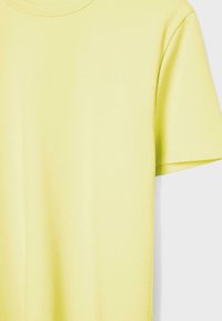 Blød, gul T-shirt med korte ærmer og rund halsudskæring, enkel i design, vist mod en hvid baggrund.