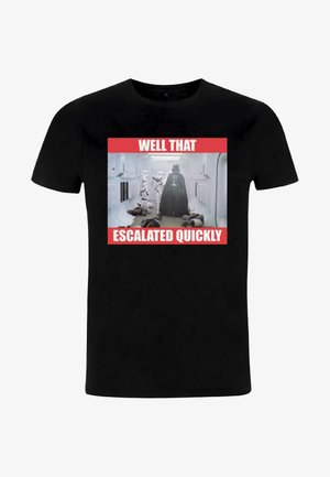 T-shirt in cotone nero con una grafica di personaggi, con testo rosso che recita "BENE, È DIVERSO VELOCEMENTE" e una scena umoristica sottostante.