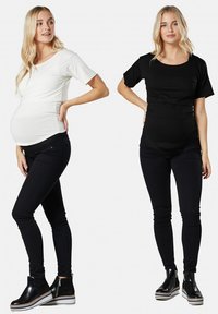 Maternity tops in white and black with short sleeves, stretch fabric, fitted design, and gathered sides; paired with black slim jeans and ankle boots.
