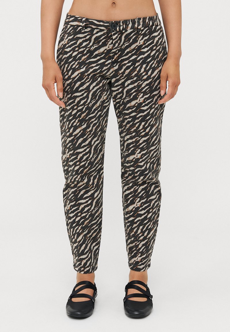 Pantaloni a fantasia neri e beige con un design affusolato e una cintura elastica, abbinati a scarpe nere flat. Presentano un dettaglio con bottone.