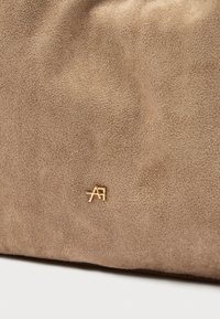 Μπεζ σουέτ θήκη με υφή στην επιφάνεια και ένα μικρό χρυσό λογότυπο ως διακοσμητικό στοιχείο. Απλός σχεδιασμός χωρίς επιπλέον διακοσμήσεις ή σχέδια.