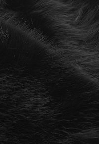 Tessuto in pelliccia sintetica nera con lunghe e morbide frange, caratterizzato da una consistenza liscia e un aspetto denso e soffice, ideale per calore e comfort.
