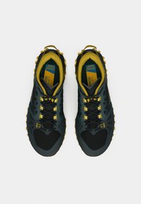 Μαύρα και πράσινα παπούτσια πεζοπορίας με κίτρινες λεπτομέρειες, με υφασμένο επάνω μέρος, δέσιμο με κορδόνια και έντονη εξωτερική σόλα για καλύτερη πρόσφυση.
