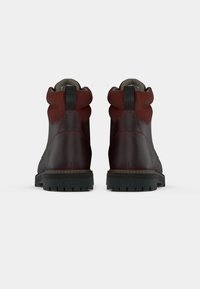 Brown leather ankle boots with a suede upper, round toe, contrasting red accents, rubber sole, and a pull tab at the back.