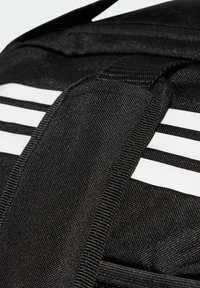 Primer plano de una correa de tela negra con costuras reforzadas sobre un fondo con tres franjas blancas horizontales.