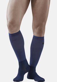 Knielange Kompressionssocken in Navyblau mit einem strukturierten Design. Sie haben eine einheitliche Farbe und kontrastierende dezente rote Akzente.