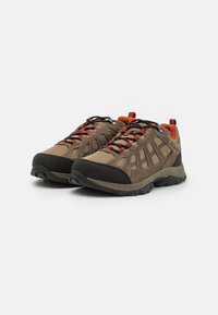 Outdoor shoes in brown and black, featuring a breathable mesh upper, red accents in laces, and a textured rubber sole for traction.