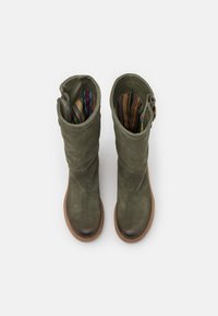 Bottes en suede vertes montantes avec un bout arrondi, présentant une doublure rayée multicolore et un détail de boucle sur le côté à la cheville.