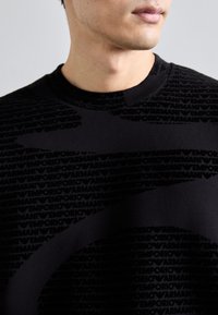 Hanorac negru cu un model texturat al logo-ului "Emporio Armani". Design cu guler rotund și mâneci scurte, fabricat dintr-un amestec moale de bumbac.