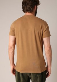 Bruine T-shirt met korte mouwen, gemaakt van zacht materiaal, met een klassieke ronde hals en een schone, eenvoudige uitstraling zonder zichtbare accenten.