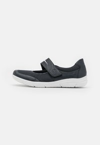 Black Mary Jane shoe featuring a textured upper with a Velcro strap and white rubber sole, designed for comfort and flexibility.