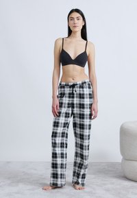 Svartvita rutiga pyjamasshorts med dragsko i midjan, kombinerade med en svart bralette. Mjukt tyg och avslappnad passform.