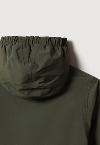 Mörkgrön lättviktsjacka med en rynkad huva, slät yta och kontrasterande sömmar.