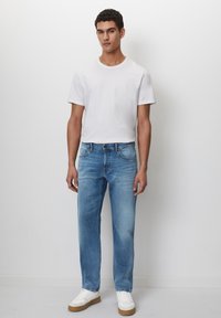 Hvit t-skjorte med rund hals, lyseblå rette jeans og hvite joggesko med en beige såle. Jevnt stoff, minimalistisk design, avslappet passform.