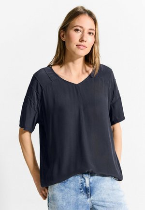 Blouse à manches courtes bleu marine foncé avec un col en V et une coupe décontractée. Présente des épaules texturées et un tissu lisse et léger.