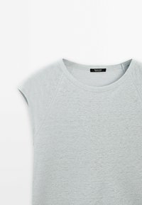 Vaaleanharmaa lyhythihainen t-paita, jossa on pyöreä pääntie ja sileä pinta. Sisältää raglan-hihat ja pienen tarran kauluksessa.