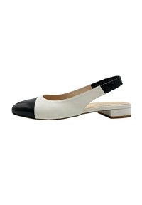 Zapato slingback con una parte superior blanca y una puntera negra, que cuenta con una correa elástica negra texturizada y un tacón bajo en bloque. Acabado en cuero suave.