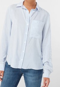 Camicia button-up a righe blu chiaro con maniche lunghe, tasca frontale e vestibilità comoda. Tessuto morbido con una superficie liscia.