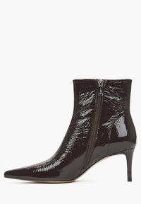 Czółenka na wysokim obcasie w błyszczącej ciemno-brązowej skórze lakierowanej, z ostrym noskiem i zamkiem błyskawicznym z boku, co ułatwia zakładanie.