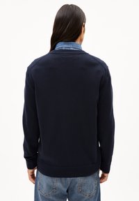 Marineblauwe gebreide cardigan met een ronde halslijn, geribde mouwen en zoom. Heeft een soepele textuur en een eenvoudig ontwerp.