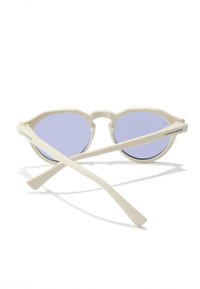 Bílé plastové sluneční brýle s šestihrannými obroučkami a světle modrými čočkami. Mají tenké nožičky s nápisem značky na boku.