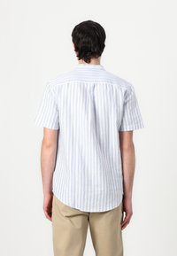 Camicia a maniche corte a righe verticali blu chiaro e bianche, realizzata in cotone, con colletto standard e orlo curvo.