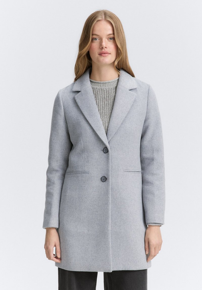 Lichtgrijze wollen jas met een notch lapel, twee knopen aan de voorkant en zijzakken; gladde textuur met een getailleerde pasvorm en minimale details.