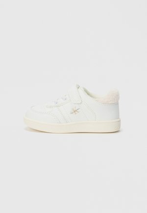 Baskets blanches pour tout-petits avec bande Velcro, détails perforés, semelle beige, col rembourré doux et petit logo Calvin Klein sur le côté.