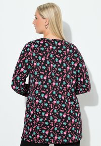 Černý top s dlouhými rukávy, který má barevný potisk sladkostí a listoví. Materiál má hladkou strukturu, volný střih a mírně prodloužený zadní díl.