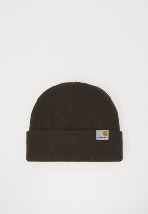 Gorro de punto marrón con un dobladillo doblado, que presenta un pequeño parche rectangular de logo de Carhartt con acentos amarillos y blancos.
