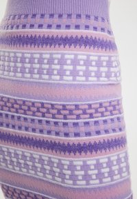 Țesătură tricotată cu modele, având nuanțe variate de violet și roz, cu desene geometrice, inclusiv pătrate și zig-zaguri, într-o textură moale.