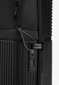 Czarny teksturowany róg twardej walizki z zamykaną na zamek częścią materiałową, podwójnymi suwakami z logo Wittchen oraz zintegrowanym zamkiem szyfrowym TSA.