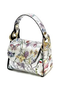 Zilveren lederen tas met bloemenpatronen, zwarte accenten, gouden hardware en een decoratieve bijsluiting; heeft een korte handgreep en een zijlabel.
