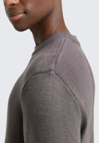Helles grauer Strickpullover mit Rundhalsausschnitt. Verfügt über ein strukturiertes Maschenmuster und Raglanärmel, die Design und Komfort nahtlos verbinden.