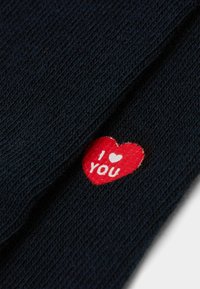 Granatowa dzianina z naszywką w kształcie czerwonego serca z napisem "I ❤️ YOU" w kolorze białym. Tekstura jest delikatna z lekko wypukłym wzorem.