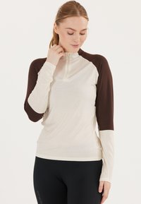 Langærmet zip-up top i creme og brun, fremstillet af letvægtsstof, med kontrastærmer og en tætsiddende pasform.