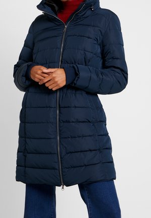 Marineblå puffjakke med quiltet design, høj krave og lynlås lukning. Har ribbet manchetter og sidelommer for ekstra funktionalitet.