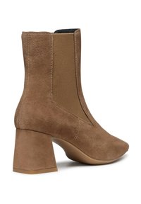 Stivaletti in suede marrone con pannelli elastici sui lati, punta affusolata e tacco a blocco. Texture liscia con finitura opaca e cuciture minime.