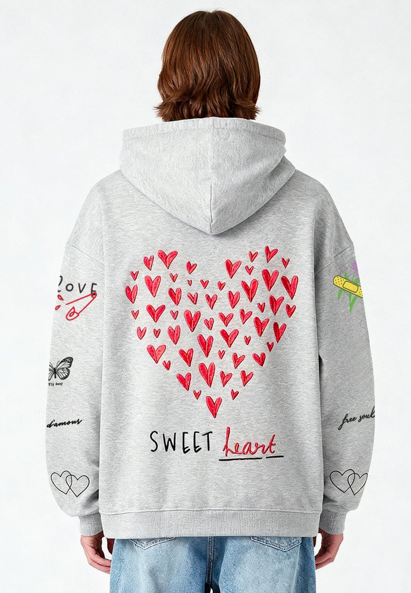 Sudadera gris con un gran diseño de corazón formado por corazones rojos en la parte posterior, con texto estilizado y varios acentos bordados en las mangas.