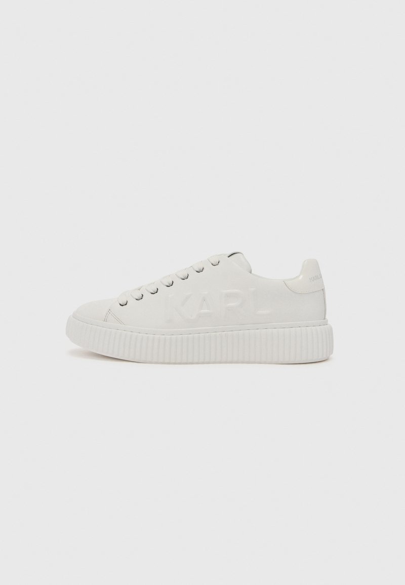 Hvite sneakers med en teksturert gummisåle og preget "KARL"-logo på siden. Har runde snørebånd og et glatt overmateriale.