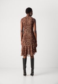 Leopardprint mouwloze jurk met gerimpelde zoom, gemaakt van sheer stof. Model draagt kniehoge zwarte laarzen. Achteraanzicht afgebeeld.