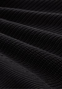 Tissu noir texturé avec un motif côtelé, montrant des détails fins et une profondeur dans le tissage, créant un aspect doux et en couches.